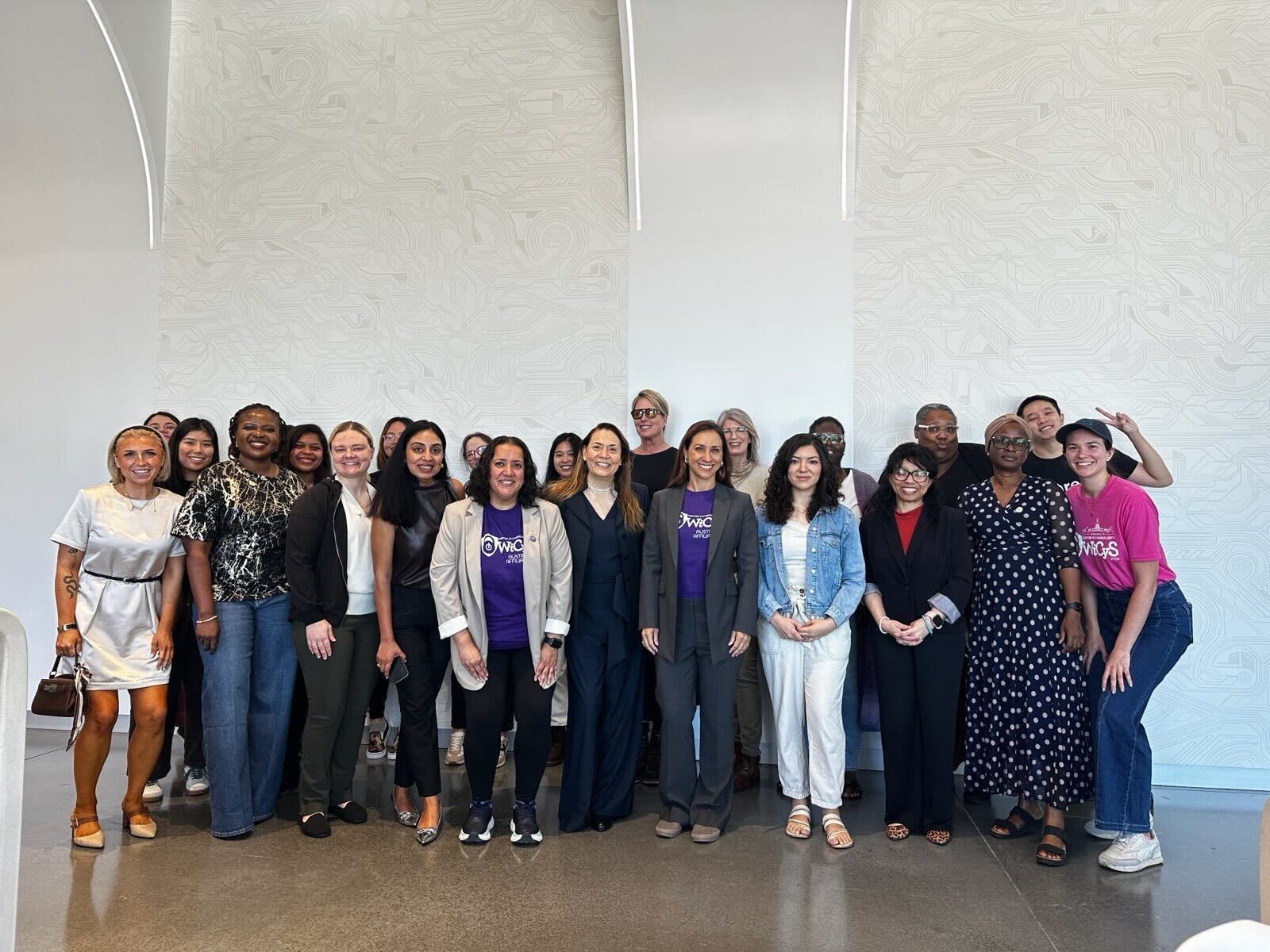 WiCyS Austin Affiliate group photo in front of a white circuit-pattern wall